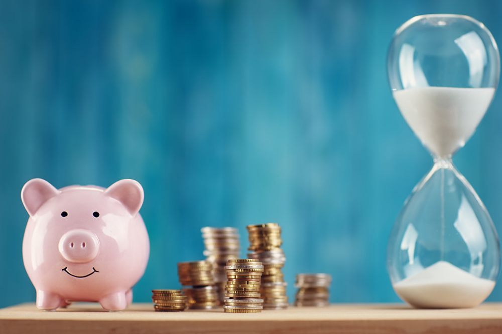 Foto: Sparschwein mit Münzen und Sanduhr